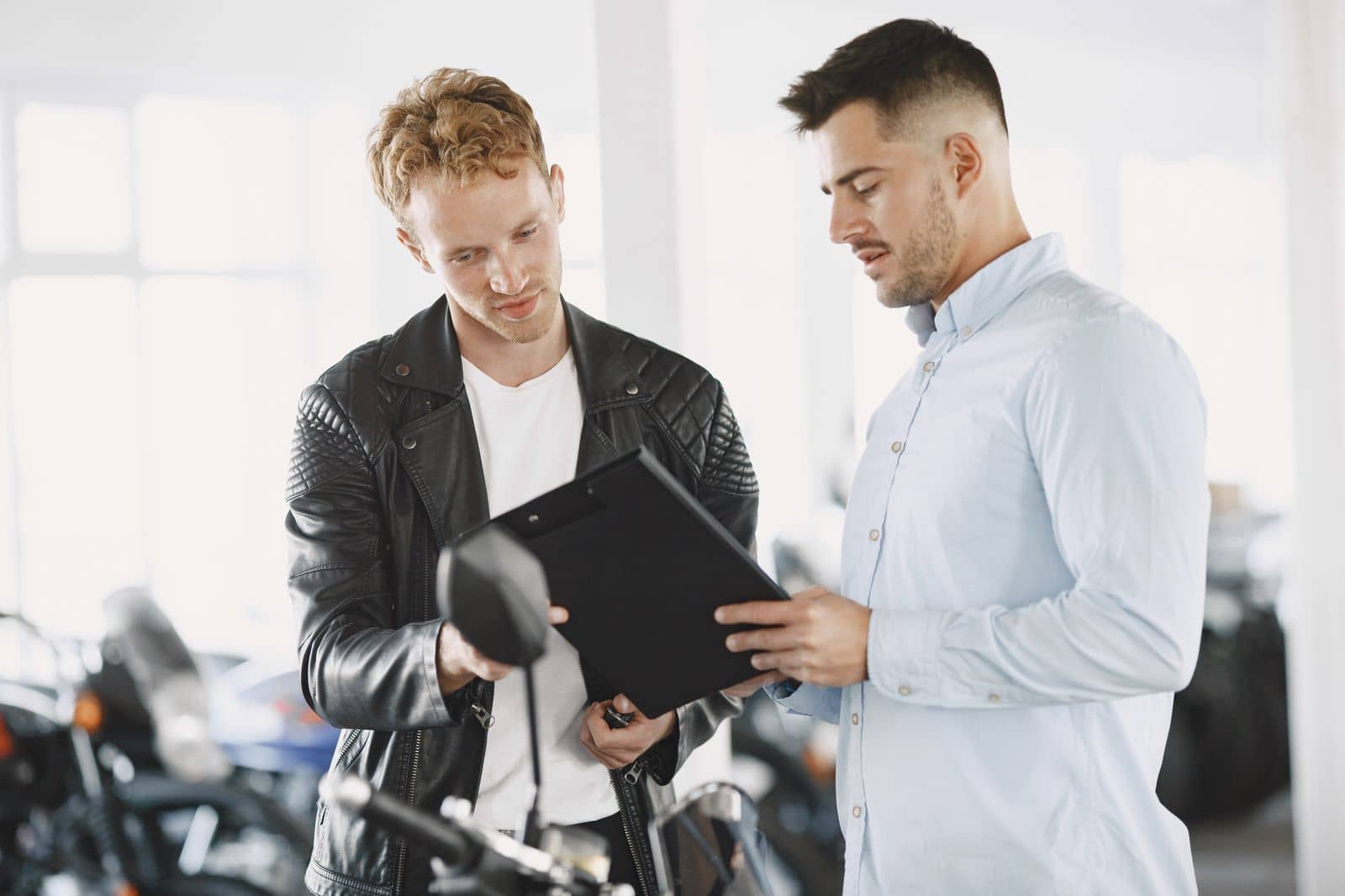 Vendedor e cliente conferindo documentos numa loja de motos